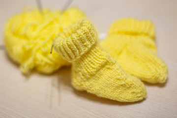 Fototapeta na wymiar little yellow knitted socks are on the table