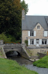 Fototapeta na wymiar Ville de Genêts, maison bretonne à volets blancs, pont et canal, département de la Manche, France