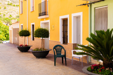 Mini trees in flower pots and chairs on a cozy Mediterranean street in the old town of Releu, Spain. Resting place