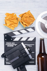 nachos, beer and equipment for shooting a film on a light background