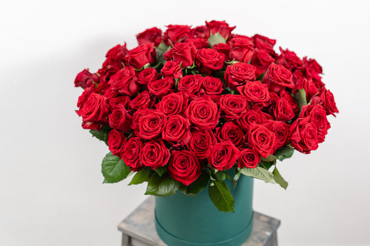 Fototapeta Big luxury bright bouquet on wooden table. One hundred of garden red roses. Color passionately scarlet, Autumn mood. bouquet in a hat box
