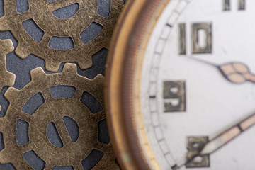 Antique pocket watch and old vintage hour metallic gears on natural stone background.