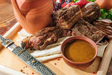 Georgian food - special meat dishesserved on a wooden plate with traditional dagger. Traditional...
