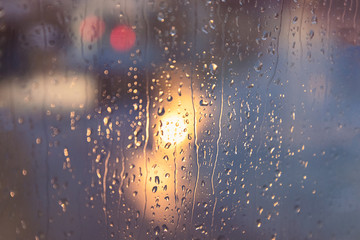 Naklejka na ściany i meble Light of a lantern and rain drops on the window. Abstract blurred background