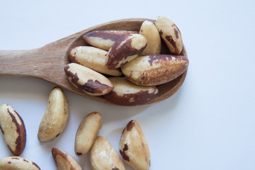 Brazil nuts in wooden spoon. White background