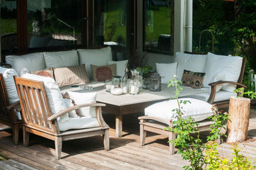 Home garden wooden furniture with table, chairs and cushions on wooden boards floor