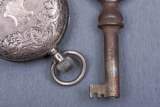 Panta rhei concept: old antique pocket watch and vintage key on natural stone background.