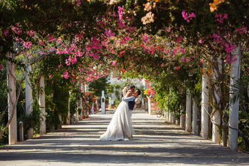 Beautiful smiling young bride and groom walking on the beach, kissing and having fun, wedding ceremony near the rocks and sea. Wedding ceremony on coast of Cyprus