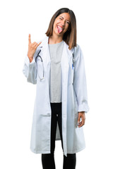 Doctor woman with stethoscope showing tongue at the camera having funny look and taking out the horns on isolated white background