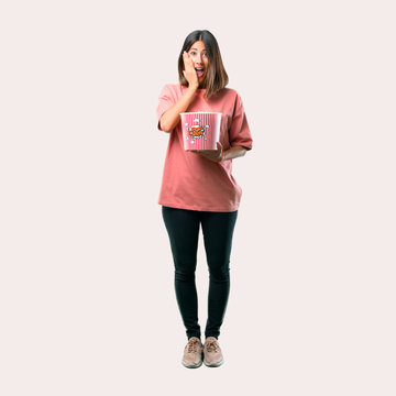 Full body of Surprised Young girl with pink shirt eating popcorns