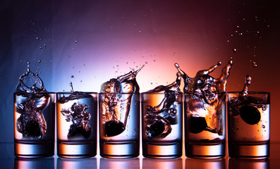 splashing fluid in a glass. That row of glasses on a blue-red background