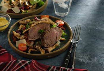 Salad with warm beef with oyster mushrooms, tomatoes and greens.