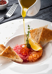 Tartar of salmon and tuna with capers, lemon and red caviar.