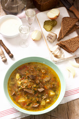 Rassolnik, traditional Russian soup, served with various snacks and vodka. Rustic style.