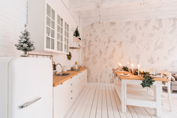 Loft style Apartment, large spacious living room with dining table and kitchen. Room with Christmas tree. Light white brick wall.