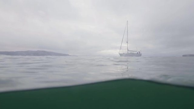 Underwater view yacht with white sail sailing in sea. Shooting while scuba diving