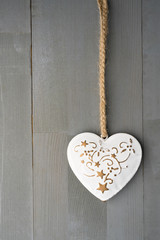 Festive heart shaped Christmas or New Year ornament with twine. Grey background. Vertical orientation. Copy space on the left.