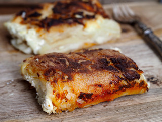 Pumpkin and cheese strudel, traditional Croatian snack called bucnica. Wooden background.