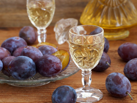 Plum brandy Slivovtz in crystal glasses and plums on wooden background. Traditional Croatian drink.