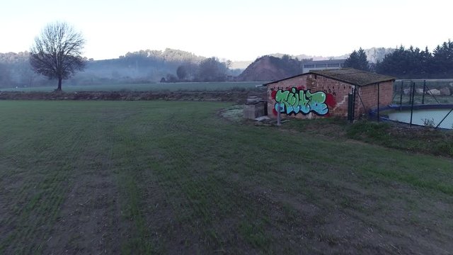4K drone footage of flight over graffiti in an old rural cottage in the middle of green fields