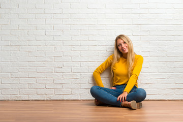 Young girl sitting on the floor posing with arms at hip and laughing