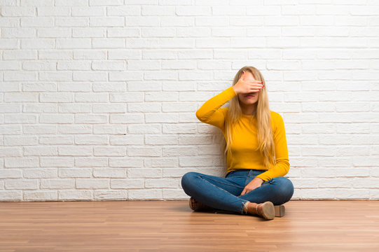 Young girl sitting on the floor covering eyes by hands. Do not want to see something
