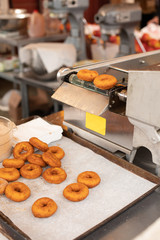 Fresh donuts falling from an automatic deep frying machine