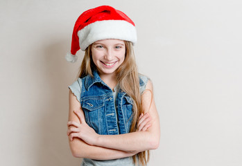 Cute young girl in santa claus hat with crossed arms