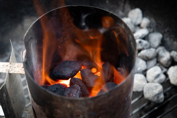 Glowing charcoal coals with flames, in a chimney fire starter