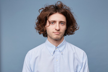 Young guy in a light shirt, with messy untidy hairstyle, long brown hair blue eyes, looking calmly...
