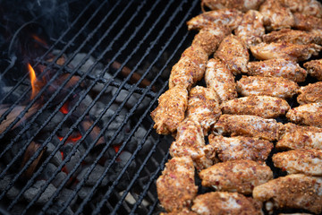 Spicy chicken wings grilling on a barbecue, with glowing coals and space for text on the left