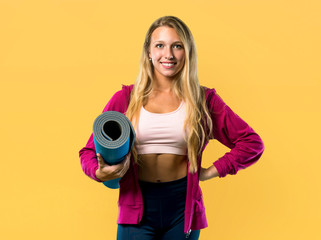 Pretty sport woman with mat on yellow background