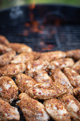 Close up on raw chicken wings grilling on a barbecue, with space for text on top