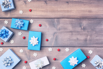 Christmas composition with copy space on wooden background. In the corner are small gift boxes, red berries and decorative snowflakes. Festive layout.