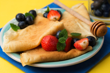 Homemade pancakes on a plate with blueberries and strawberries.