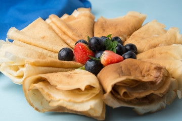 Homemade pancakes on a plate with blueberries and strawberries.