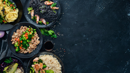 A set of food and dishes. Pasta, rice, risotto, salad. On a black background. Free copy space.