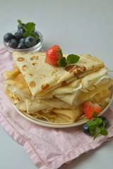 Homemade pancakes on a plate with blueberries and strawberries. Vertical image Food photo.