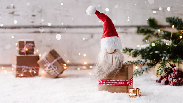 Frohe Weihnachten - Kleiner Weihnachtswichtel sitzt auf einem Geschenk und freut sich auf Heiligabend