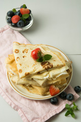 Homemade pancakes on a plate with blueberries and strawberries.