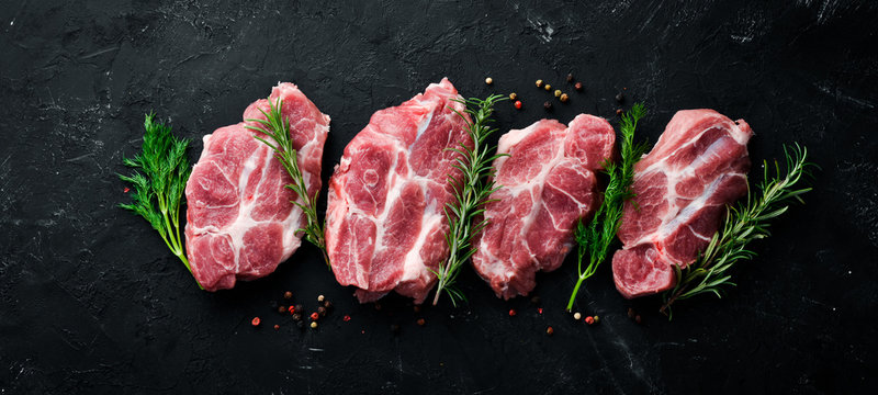 Raw steak. Meat with spices and herbs. On a black stone background. Top view. Free copy space.