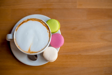 Tasty sweet macarons and coffee cup. Macaroons on wood background. Top view.