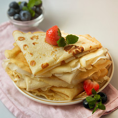 Homemade pancakes on a plate with blueberries and strawberries. Square image. Food photo.