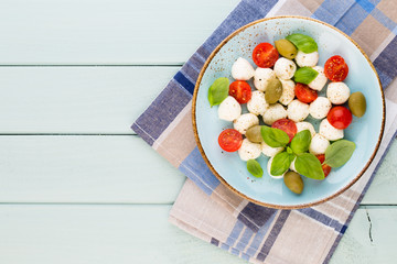 Delicious caprese salad with ripe cherry tomatoes and mini mozzarella cheese balls with fresh basil leaves.