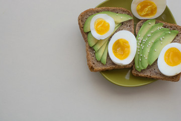 Egg and avocado on whole grain toast on green plate. Healthy eating, healthy breakfast, diet food concept. Closeup , top view