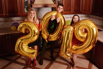 New 2019 Year is coming. Group of cheerful young people carrying gold colored numbers and have fun at the party