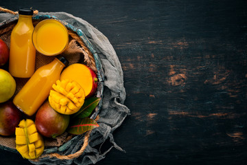 Mango and juice in a wooden box. On a wooden background. Tropical Fruits. Top view. Free copy space.