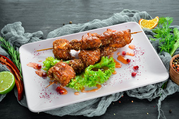Chicken shish kebab with sesame seeds and barbecue sauce. On a wooden background. Top view. Free space for your text.