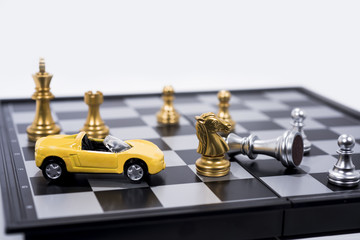 Chess Board isolated on white background. Golden and silver figures with small yellow car