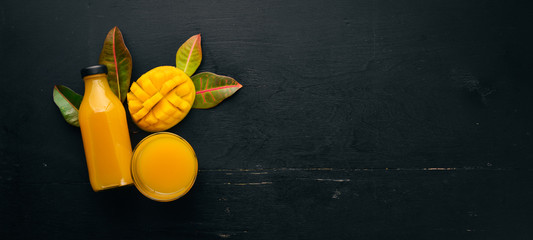 Mango and fresh juice on a black wooden background. Tropical Fruits. Top view. free space for your...